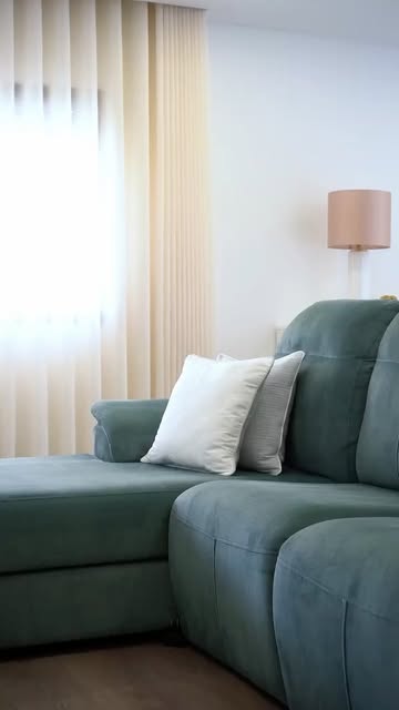 Sala de um apartamento T3 no Entroncamento, com sofá verde e luz natural